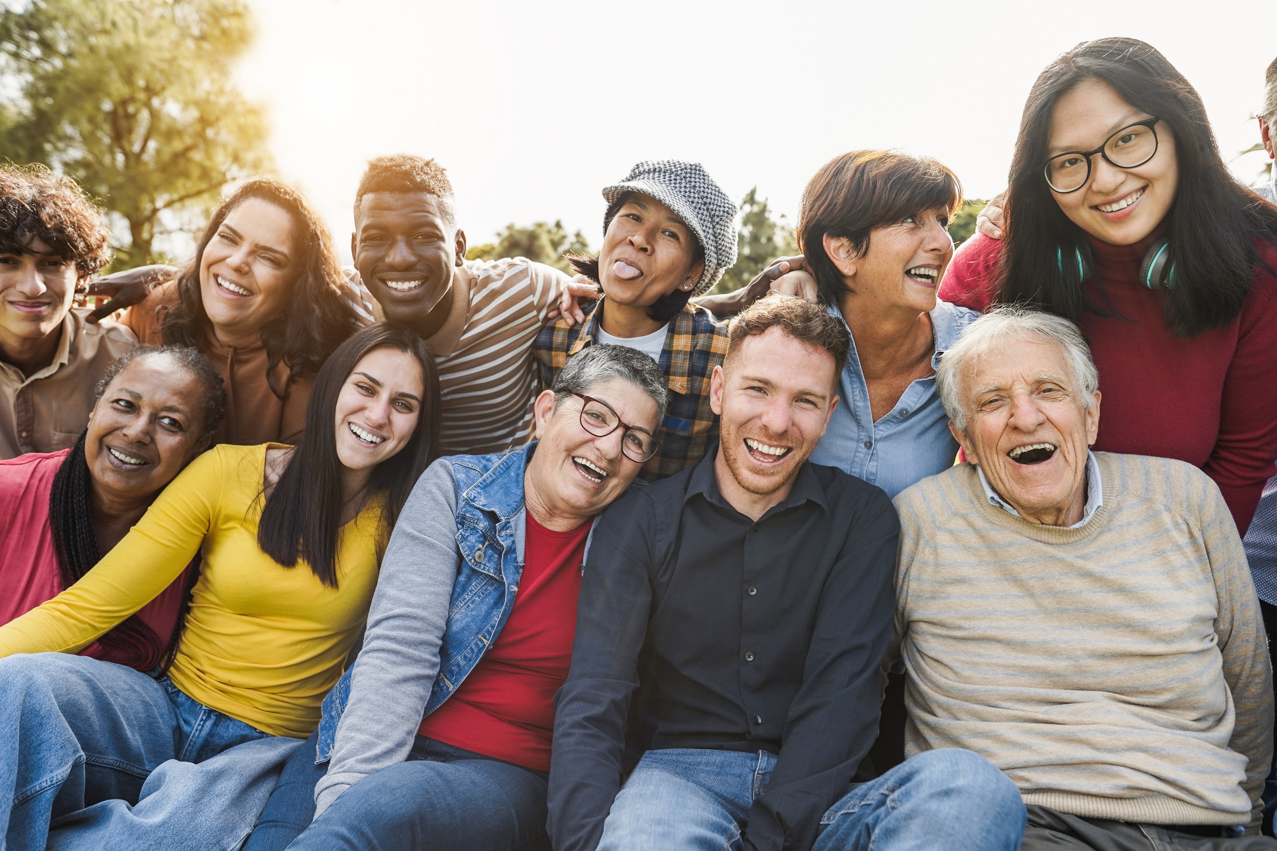 Group of multigenerational people smiling in front of camera - Multiracial friends of different ages having fun together - Main focus on caucasian senior faces