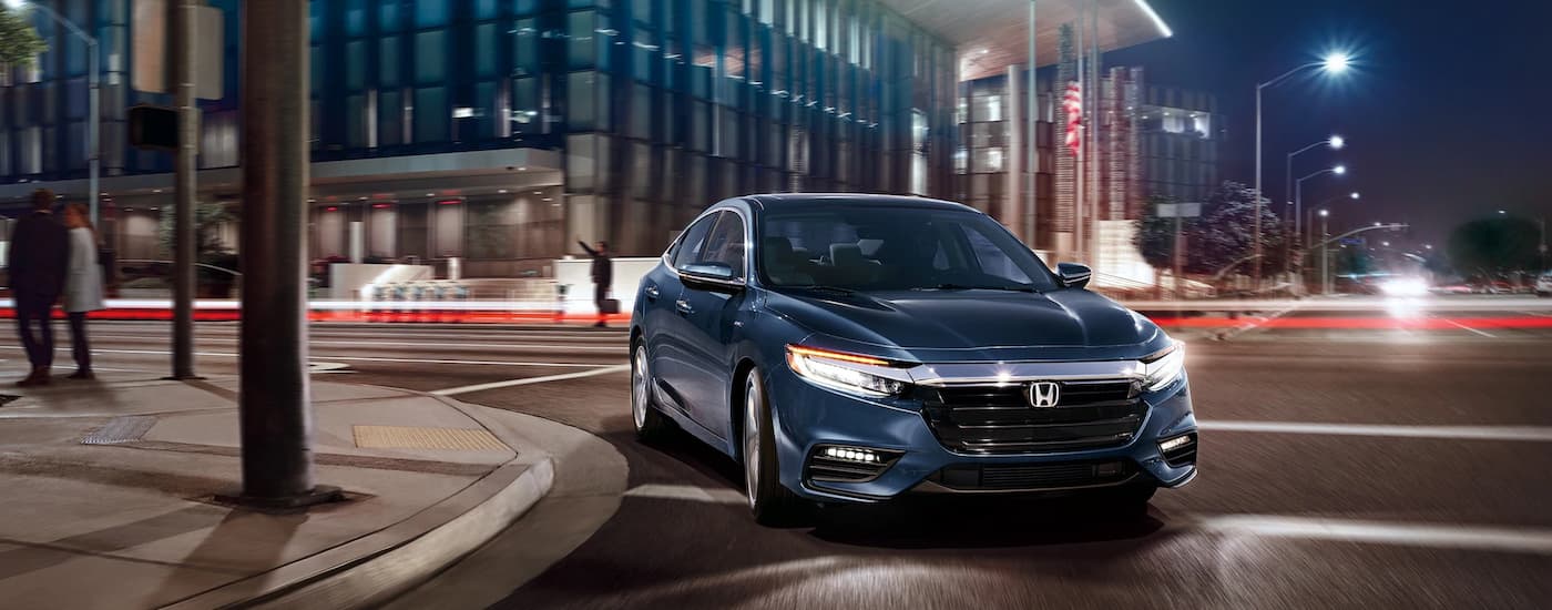 Blue 2021 Honda Insight Touring driving around a corner in a city at night