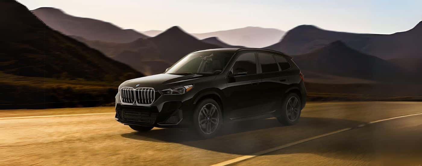 A black 2024 BMW X1 driving to view a used BMW for sale in [[city]].