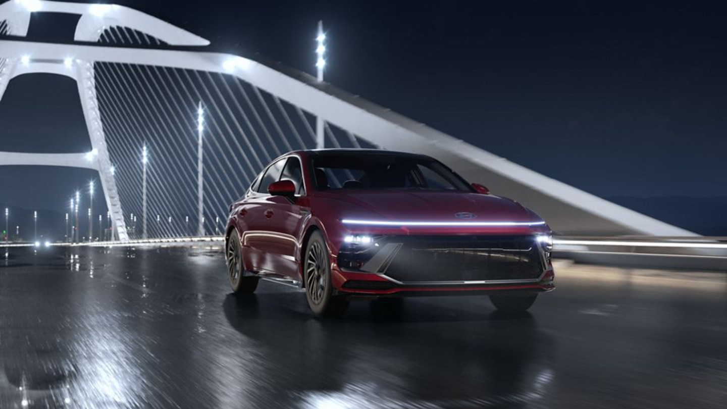 A red car driving on a bridge.
