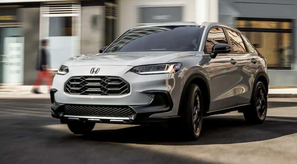 A white 2025 Honda HR-V Sport is shown driving to visit Honda dealers in Rochester.