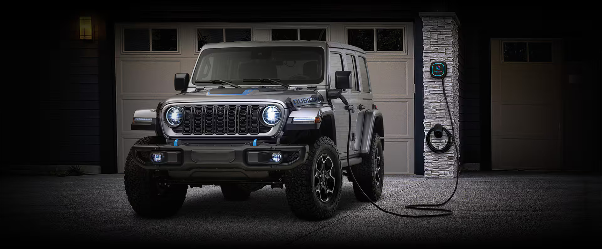 A gray Jeep Wrangler parked in the driveway charging.