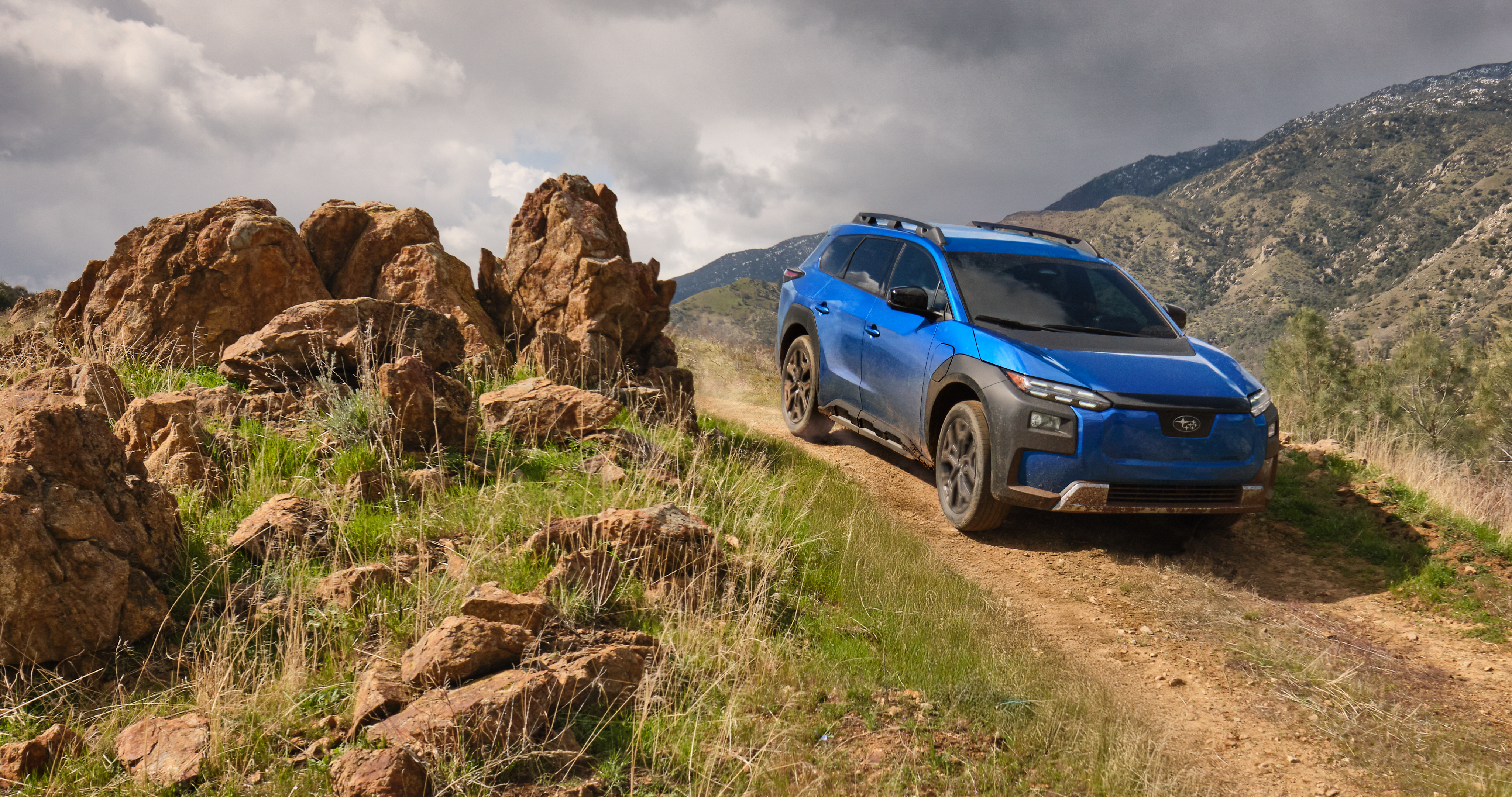 26_TSK_overview_hero_lg_xl.png / A 2026 Subaru Trailseeker in blue drives down an arid hill.
