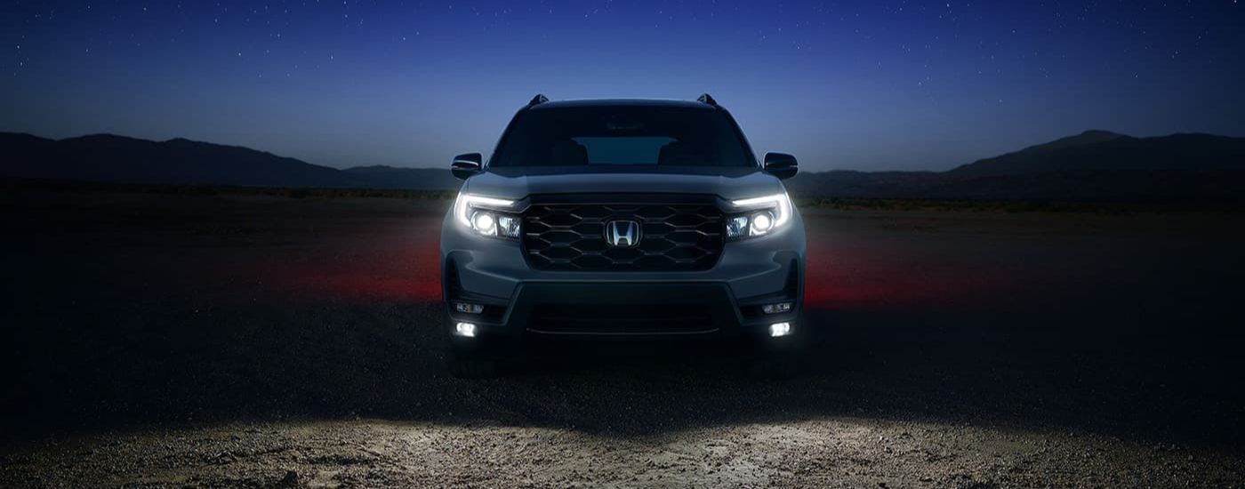 A silver 2025 Honda Passport Black Edition is shown parked at night.