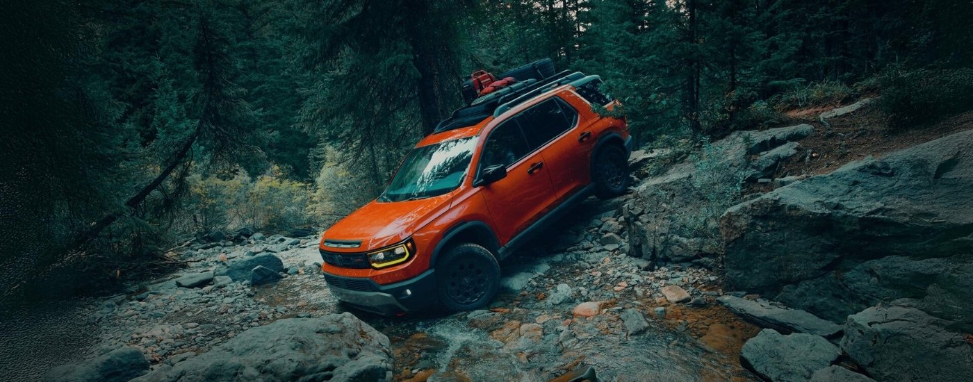 Orange 2026 Honda Passport TrailSport Elite driving downhill