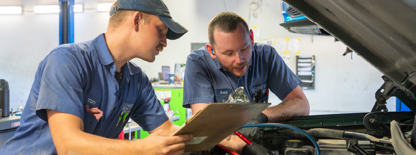 Master technician and mainline technician looking at a vehicle engine bay