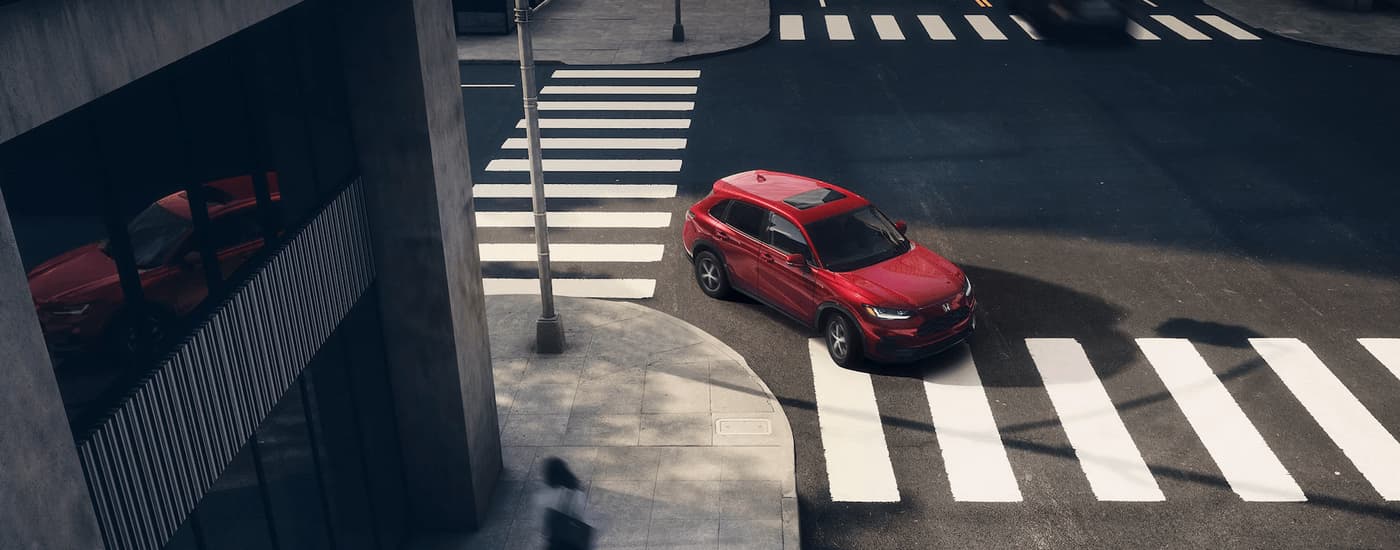 A red 2023 Honda HR-V EX-L is shown rounding a corner after visiting a Honda dealer.