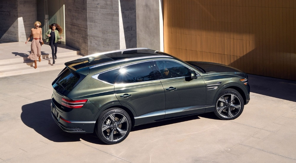 A green 2025 Genesis GV80 parked in a driveway.