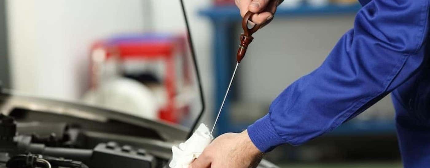 A mechanic is shown holding a dipstick while checking the oil level.