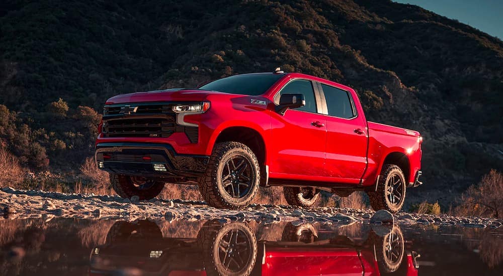 Red Chevrolet Sivlerado 1500 driving off road near a lake