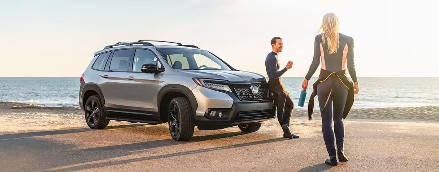 People in wetsuits are approaching a silver 2020 Honda Passport Elite
