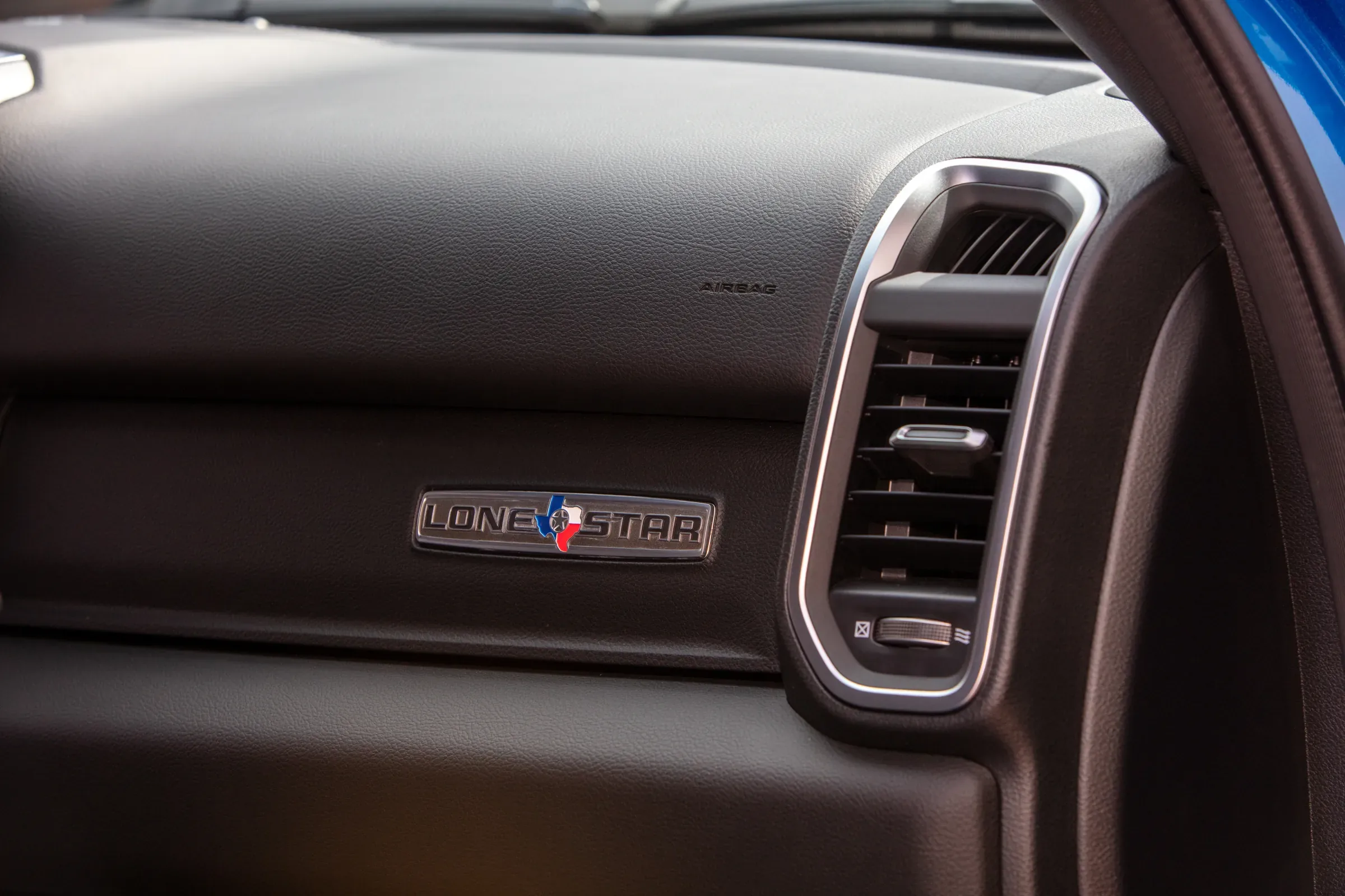 Close-up of a Ram truck's dashboard featuring the Lone Star trim badge next to an air vent. Vehicle A/C Service Near Kansas City