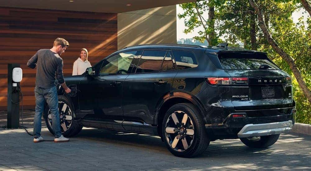 A black 2026 Honda Prologue parked in a driveway charging