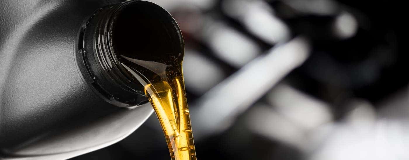 A close up of oil is shown being poured into an engine.