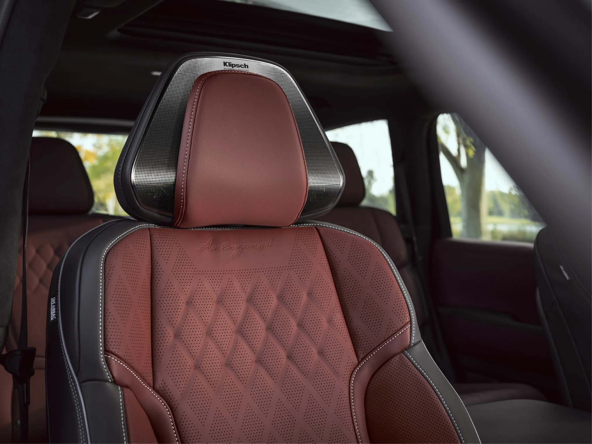 Burgundy diamond-quilted Autograph leather seat in the 2027 INFINITI QX80 with Klipsch speakers integrated into the metallic headrest frame.