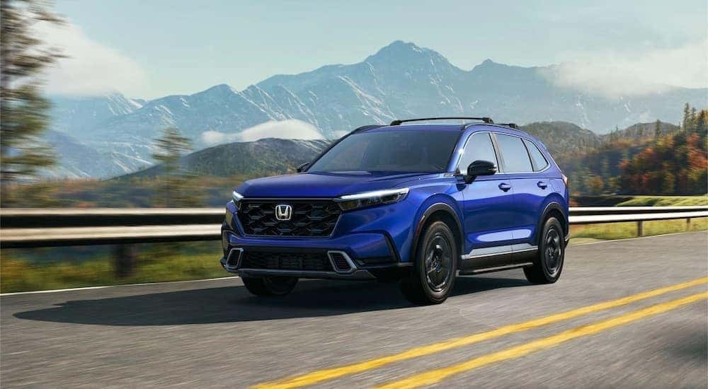 Blue 2023 Honda CR-V driving down a road