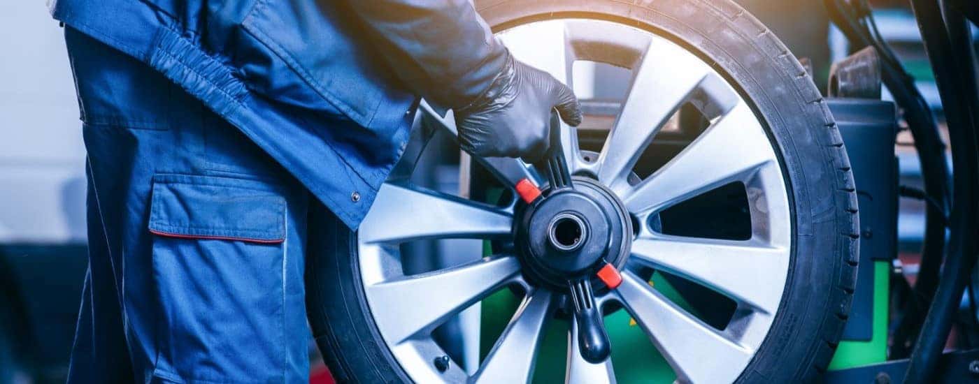 A close-up shows a tech balancing a a wheel at a tire shop near Irondequoit.
