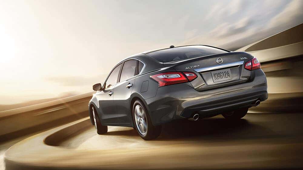 Gray 2017 Nissan Altima sedan driving on a curved road, rear three-quarter view