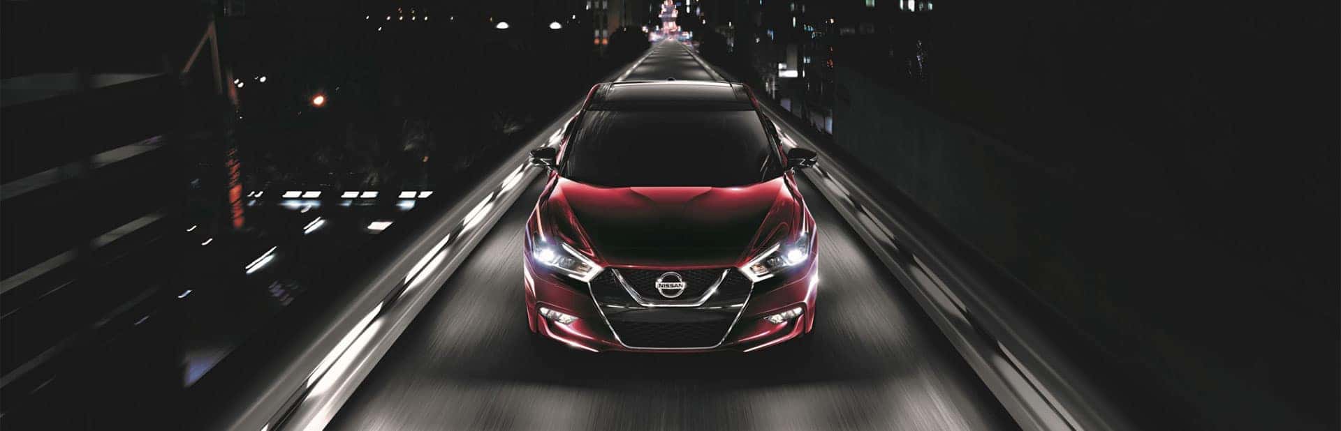 Red Nissan Maxima driving through a tunnel at night