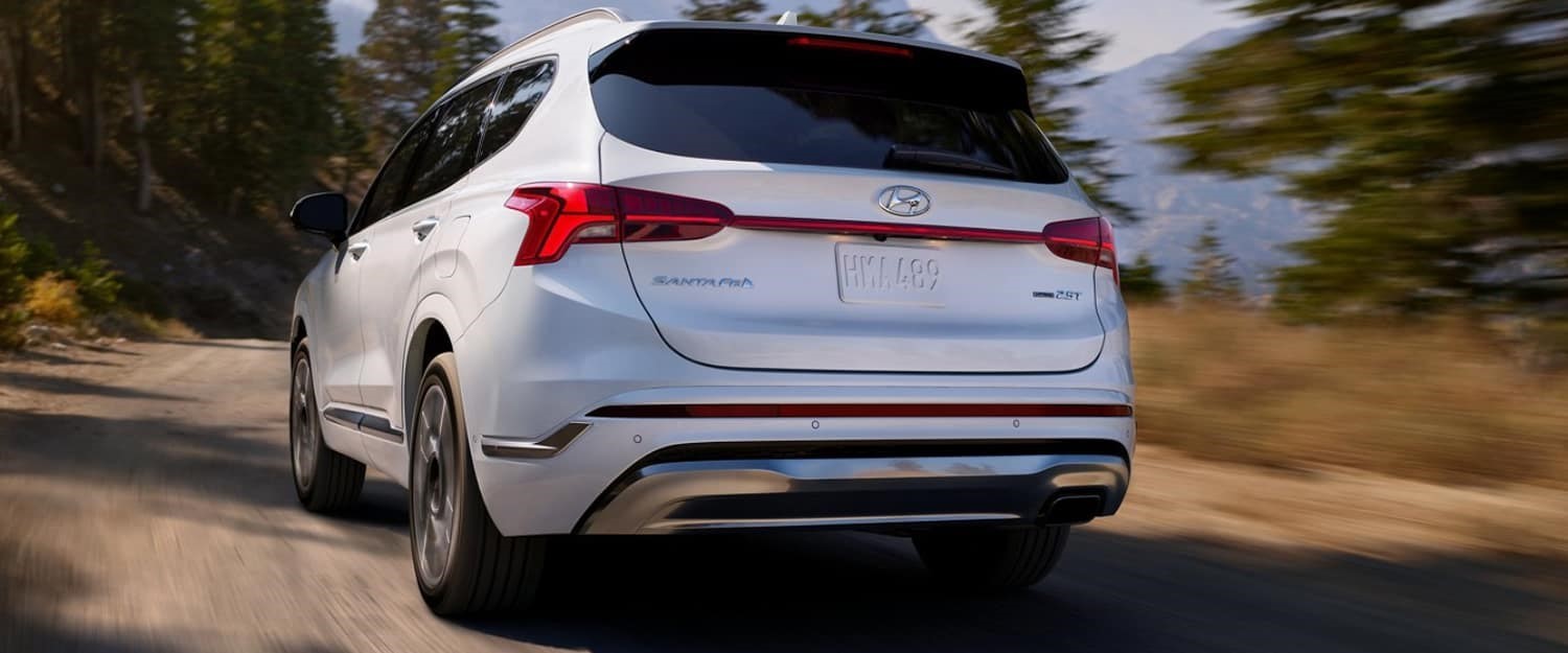 A white 2021 Hyundai Santa Fe driving on a dirt road.