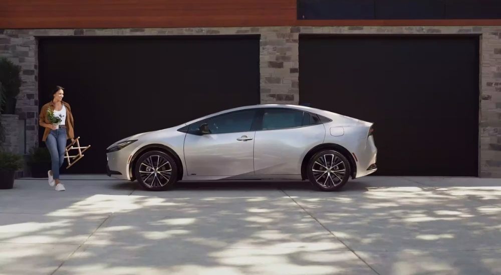 Woman carrying a plant next to a silver 2023 Toyota Prius Limited
