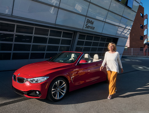 Woman sitting in the driver’s seat of a BMW vehicle with display screen visible.