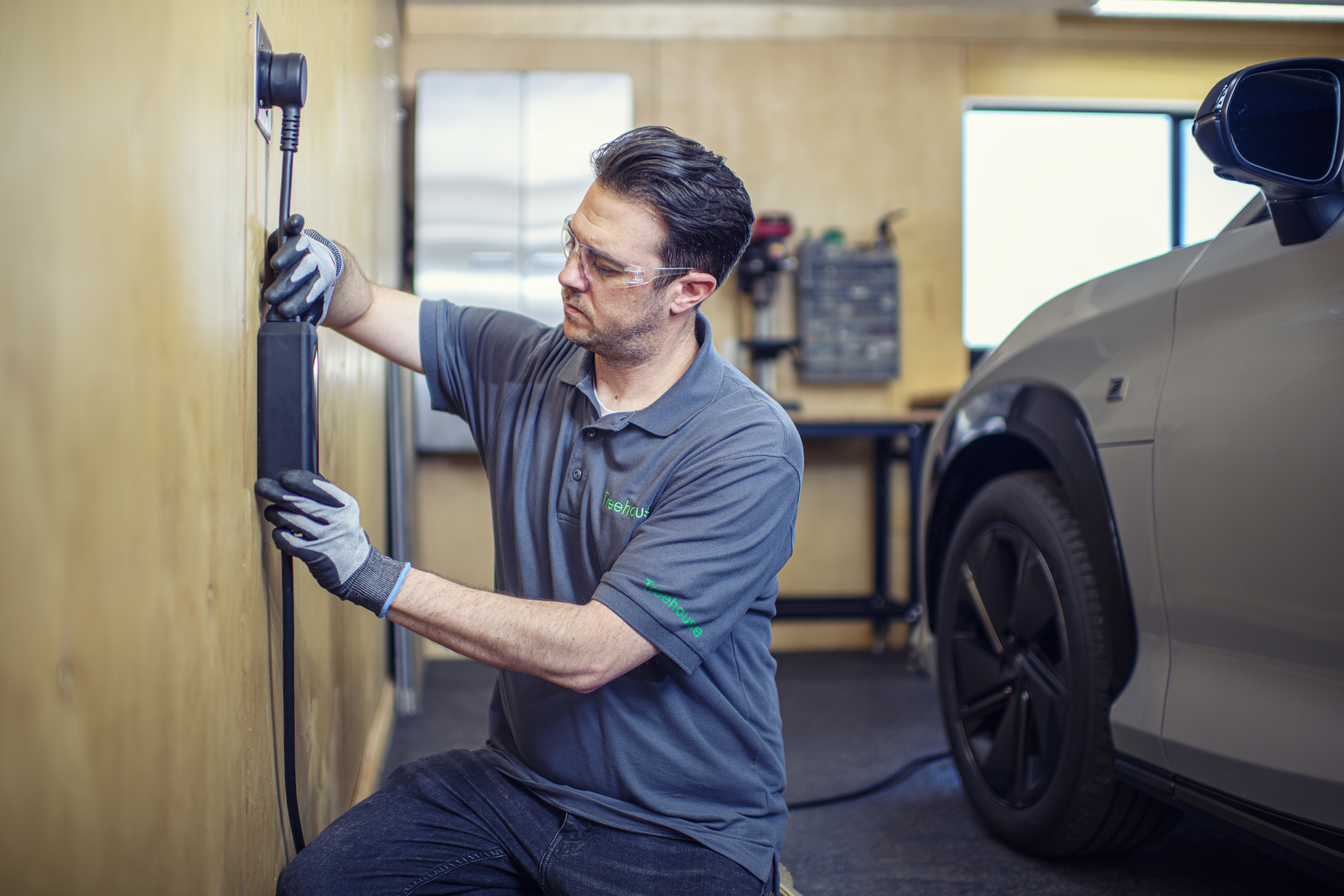A person plugs a charger into their vehicle's charging port.