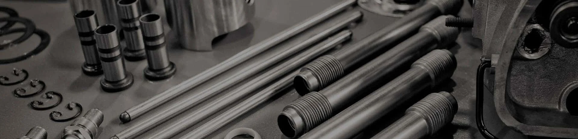 Nissan engine parts including valves, pushrods, pistons and washers laid out on a workbench