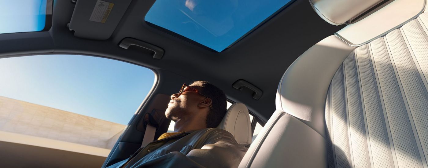 A person enjoying the sunroof in a 2026 Genesis G70.