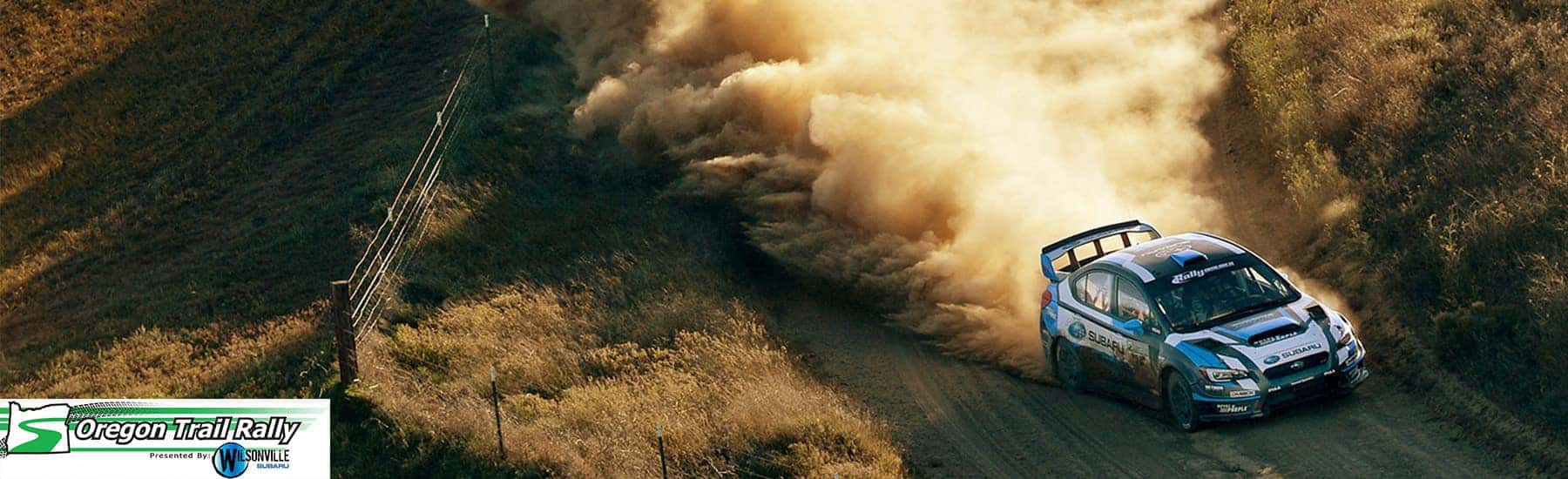 Subaru rally car kicking up dust on a gravel stage