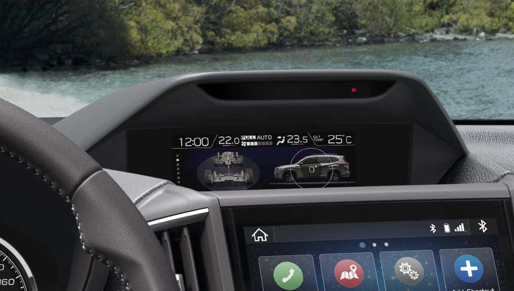 Subaru center display showing X-MODE settings, with a river visible through the windshield