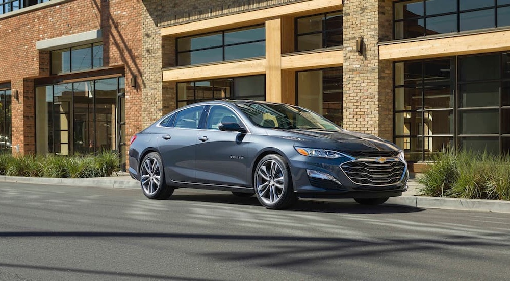 A gray 2020 Chevy Malibu is shown parked near used cars for sale.