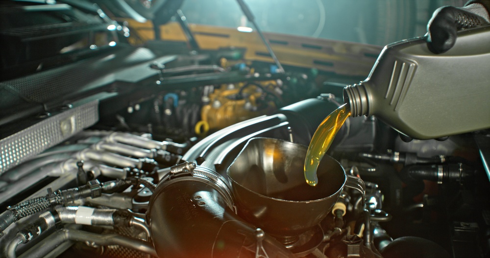Gray Canister Pouring Synthetic Oil into Vehicle