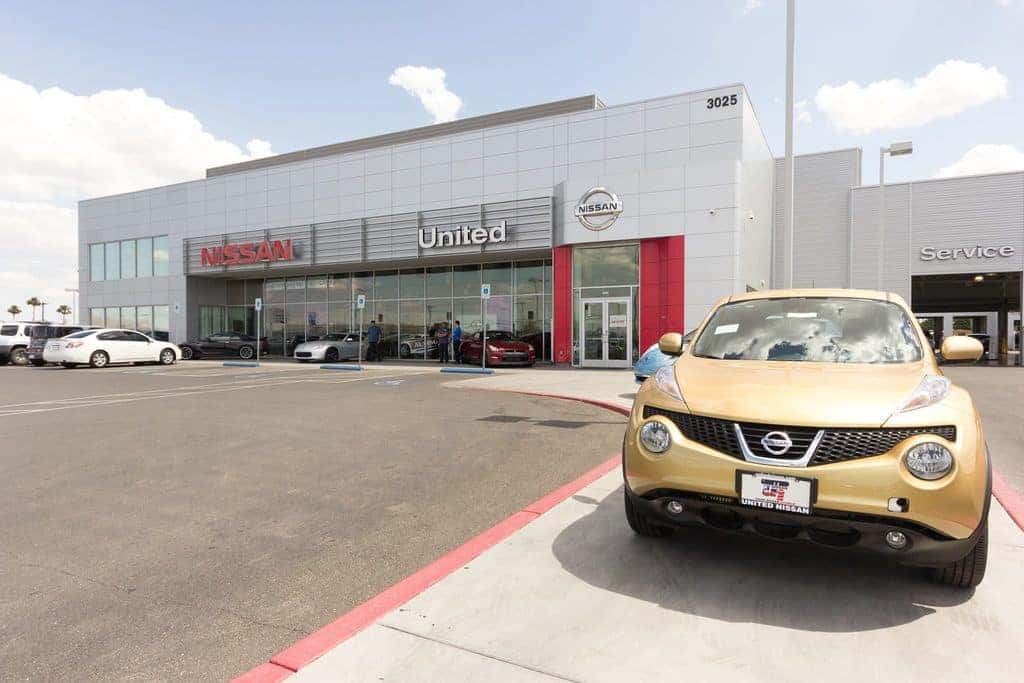 United Nissan dealership storefront in Las Vegas with a gold Nissan Juke parked out front