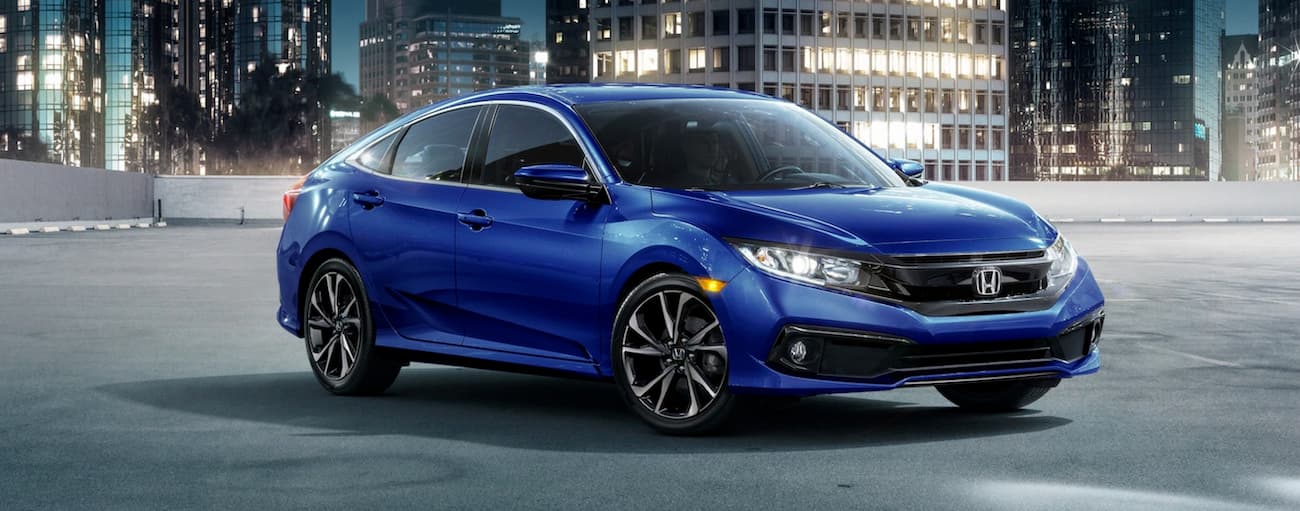 A blue 2019 Honda Civic, from a used Honda dealer in Rochester, is shown parked in the city at night.