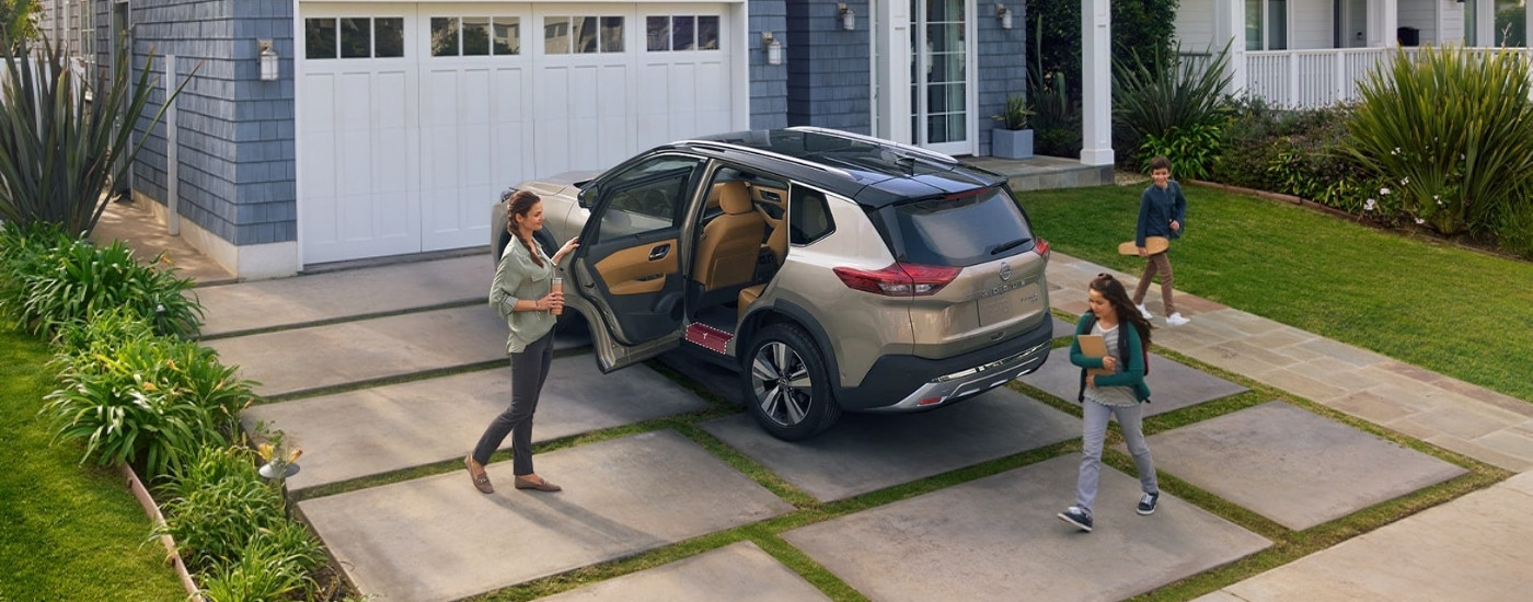 Nissan Rogue 2023 color arena estacionado en la entrada de autos