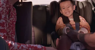 Person buckling an infant into a baby seat