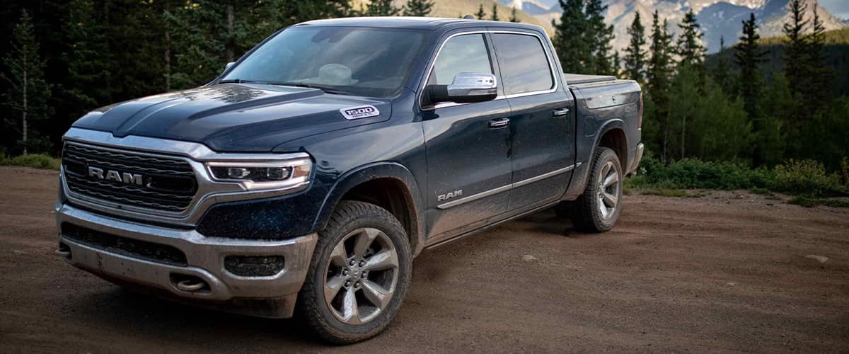 A ram truck sitting on a dirt road.