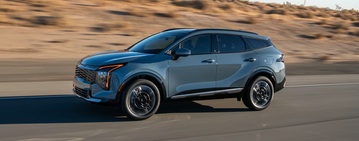 Blue 2026 Kia Sportage Hybrid driving down an open road.