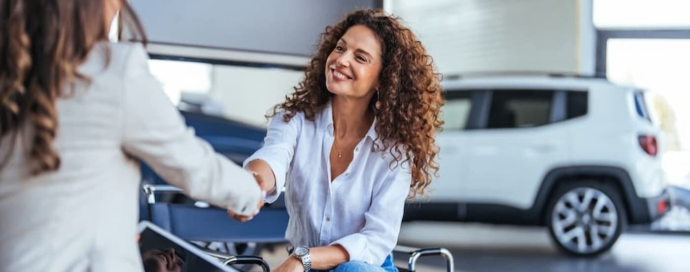 Two people shaking hands at a dealership.