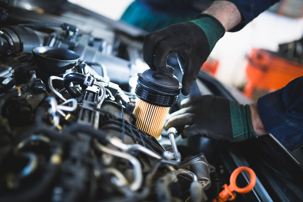 mechanic working with an air filter under the hood of a vehicle