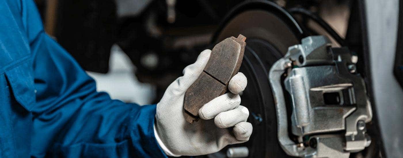A mechanic is shown holding up a brake pad.