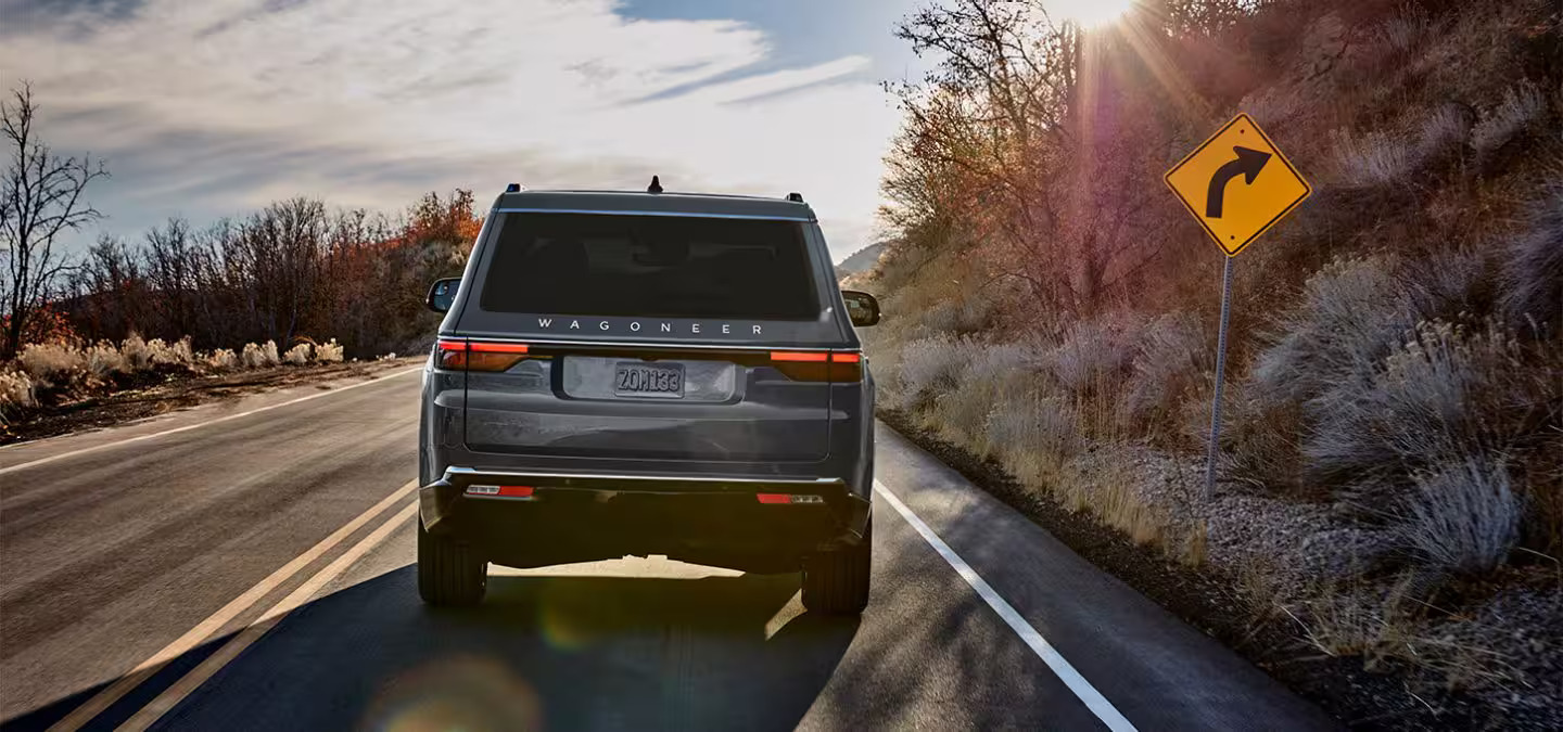 A silver suv driving on a road.