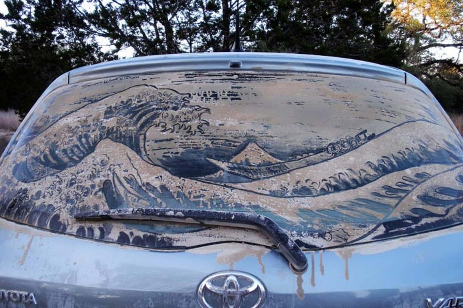 Wave drawing traced in dust on a dirty rear car window