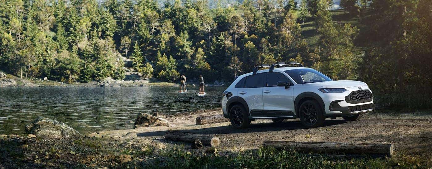 A white 2025 Honda HR-V parked in the sand near a lake.
