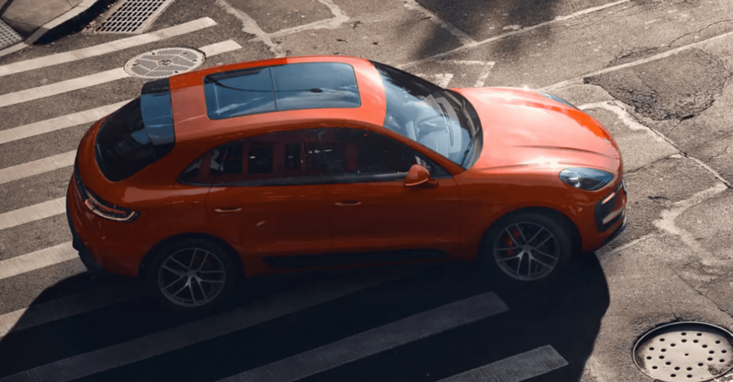 A red Porsche Macan EV turning down a street.