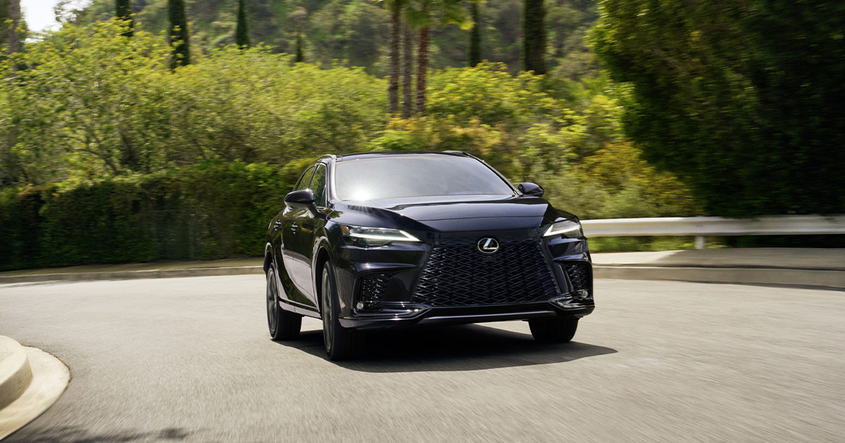 A black Lexus RX rounding the corner driving up a curved street.