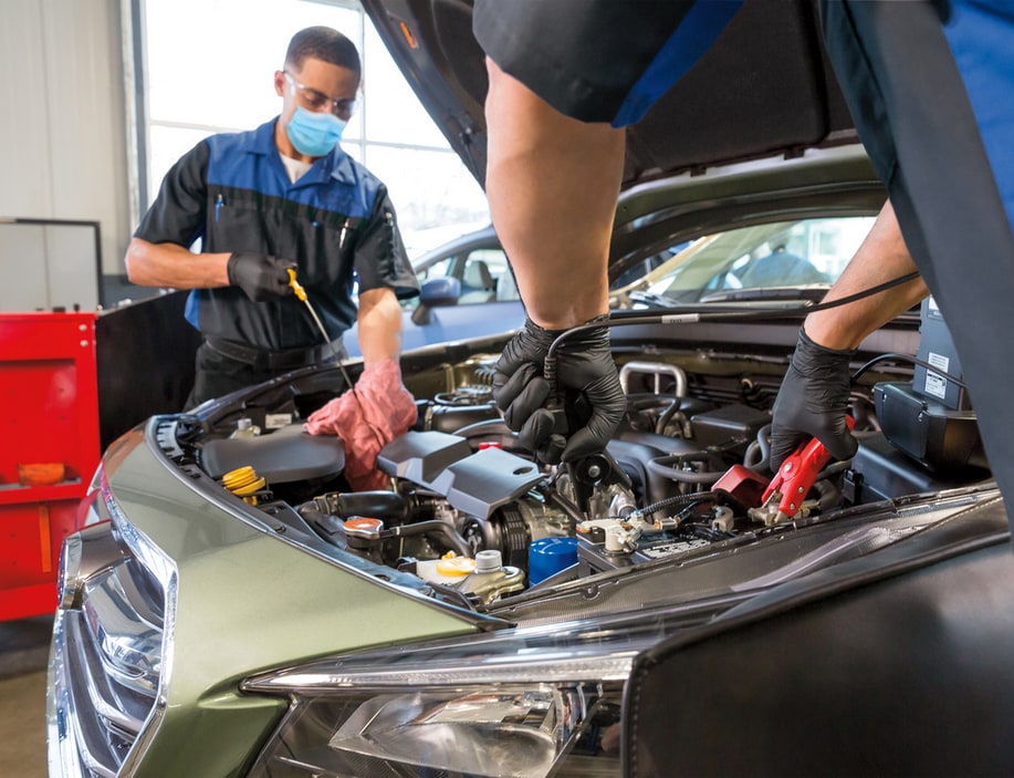 Two Subaru technicians performing maintenance on a Subaru engine compartment.