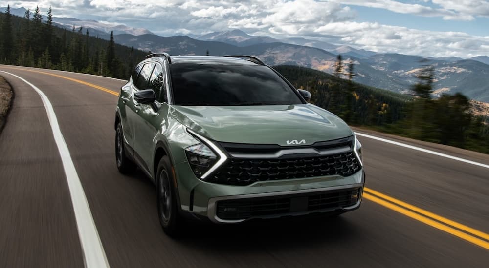 Green 2025 Kia Sportage driving to a Kia dealer