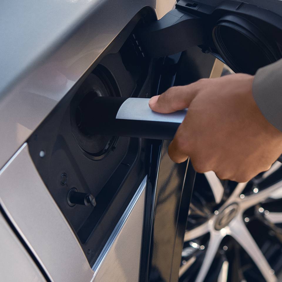 A person plugs a charger into their vehicle's charging port. 